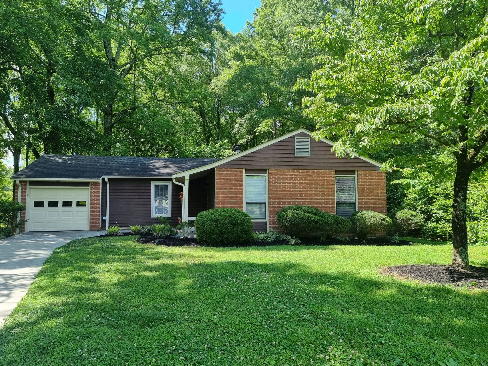 Front view of brick ranch home surrounded by trees